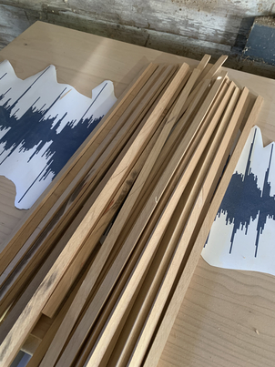 Thin strips of stock cut and laying on project base against template.